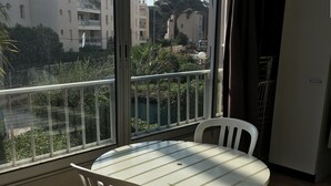 A balcony with a round table and two chairs, overlooking a residential area with buildings and greenery.