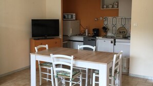 A compact kitchen with a dining table and chairs, a microwave, a coffee maker, and a television.