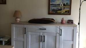 A room with a white cabinet, a lamp, a radio, and a painting on the wall.