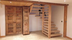 Een houten trap met een inbouwkast, een houten deur en een betegelde vloer.