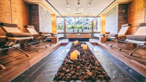 Un área de spa con paredes de madera, suelo de piedra y vistas a montañas a través de amplios ventanales.
