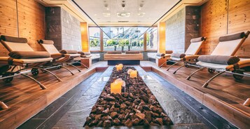 Un área de spa con paredes de madera, suelo de piedra y vistas a montañas a través de amplios ventanales.