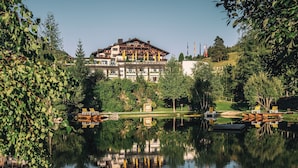 Un hotel de varios pisos, reflejado en el agua y rodeado de un jardín.