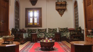 Una habitación tradicional con un conjunto de sofá de madera, un tapete estampado y una mesa de centro decorativa.