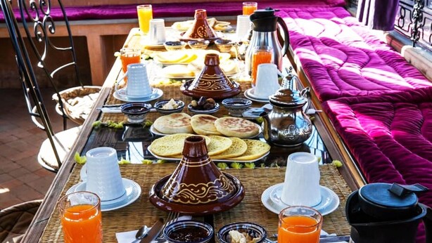 Un bufé de desayuno con diversos platos, bebidas y teteras tradicionales marroquíes.