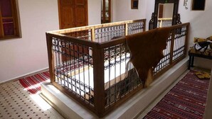 Una escalera con barandilla de madera y balaustrada de metal, que conduce a un rellano con alfombra estampada.