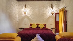 Una habitación con una cama grande, dos mesitas de noche y una pequeña mesa con una bandeja decorativa.