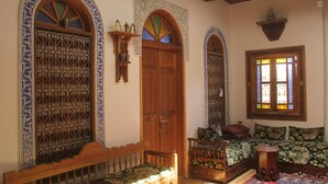 Una habitación tradicional con una cama de madera, un banco y una mesita.