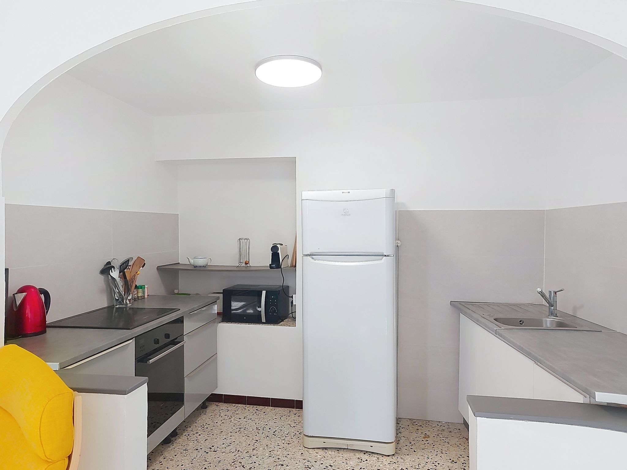 A compact kitchen with a white refrigerator, a microwave, a sink, and a stove.