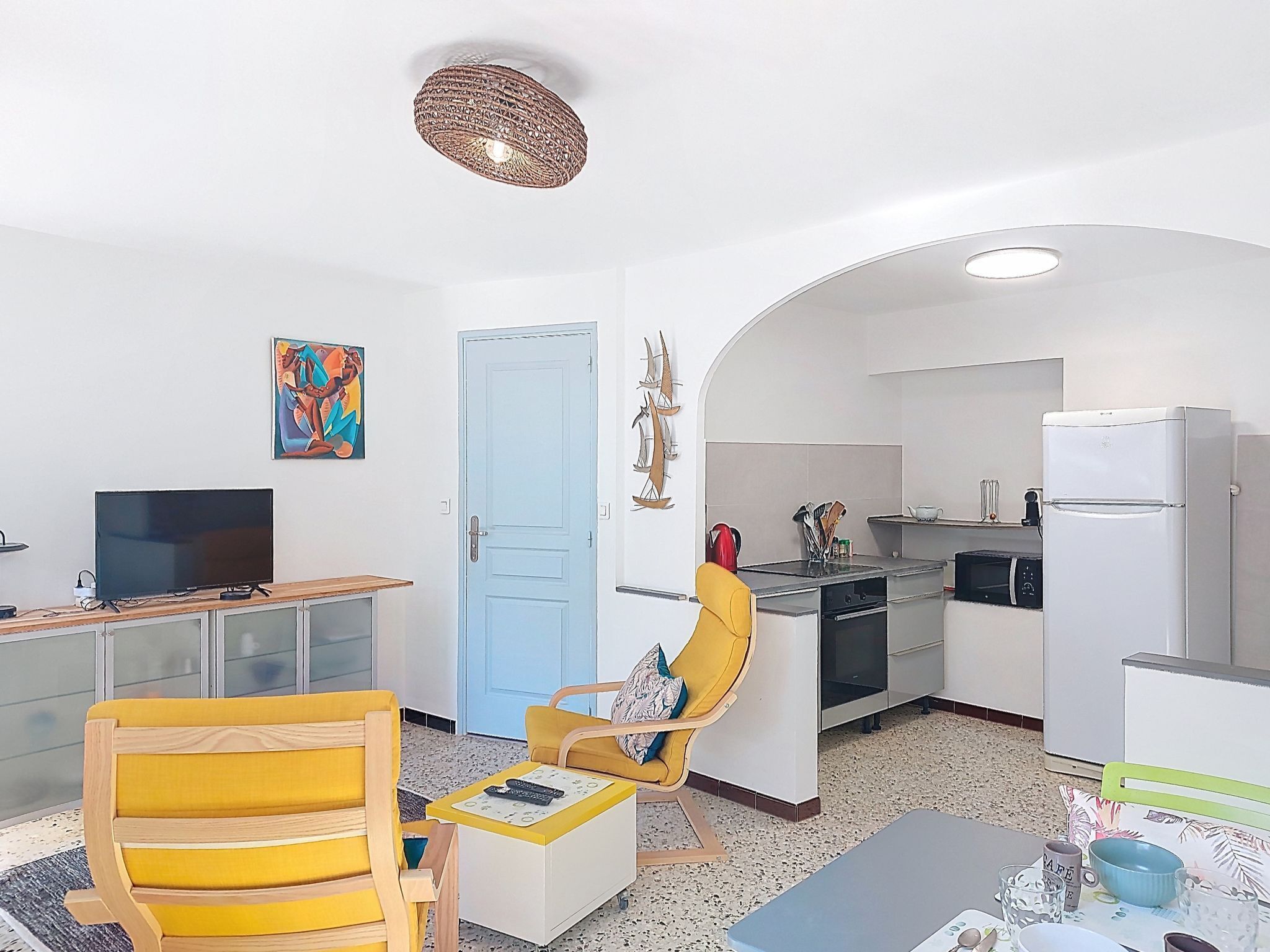 A compact living space with a kitchenette, a dining area, and a TV.