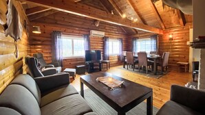 A cozy log cabin interior with a living room, dining area, and a fireplace.
