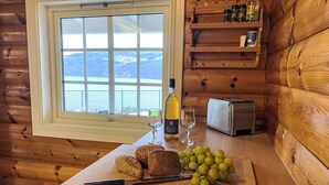 A wooden cabin interior with a window overlooking a mountainous landscape.