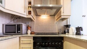 Een kleine keuken met een magnetron, oven en koffiezetapparaat.