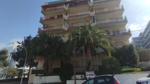 Een meerlaags woongebouw met balkons, palmbomen en een bordje met de tekst 'LA GAVINA'.