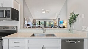 A modern kitchen with a built-in dishwasher, stainless steel appliances, and a large window overlooking a living area. - Modern, Cozy, & Quiet - Sea Pines, Near Beach (Hilton Head Island)