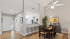 A modern kitchen with white cabinets, a dining area with a wooden table and chairs, and a ceiling fan. - Modern, Cozy, & Quiet - Sea Pines, Near Beach (Hilton Head Island)