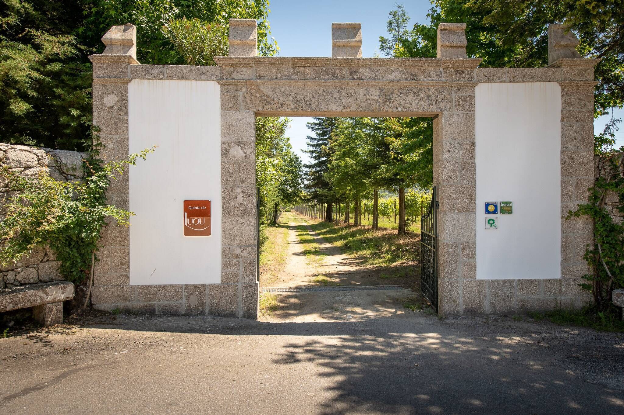Un arco de piedra con un letrero que dice "Olivet de Luou" y un símbolo de reciclaje.