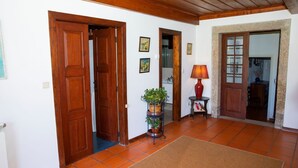 A hallway with wooden doors, a potted plant, a lamp, and a tiled floor. - Casa de Luou ground floor at Quinta de Luou (Ponte de Lima)