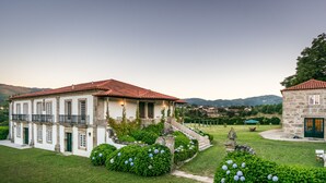 A large, white building with a red-tiled roof, surrounded by well-maintained gardens and a stone structure. - Casa do Tanque at Quinta de Luou (Ponte de Lima)