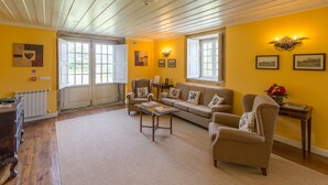 A living room with a wooden ceiling, yellow walls, a sofa, armchairs, a coffee table, and a small side table with a vase. - Casa do Tanque at Quinta de Luou (Ponte de Lima)