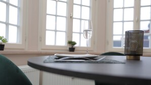 A dining area with a table, chairs, a glass of water, a menu, and a decorative item.