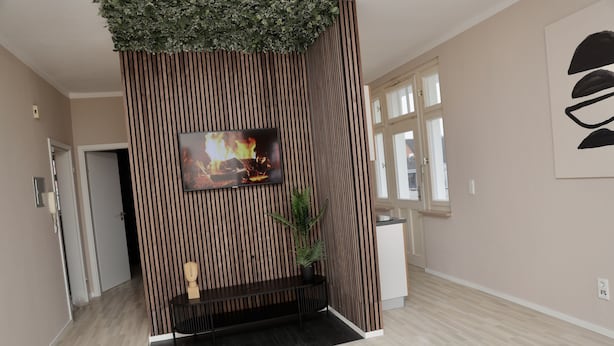 A modern interior with a wooden panel wall, a flat-screen TV, a potted plant, and a bench.