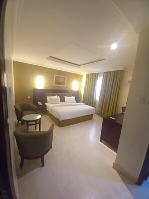 Une chambre d’hôtel avec un lit, un bureau, une chaise et une petite table.