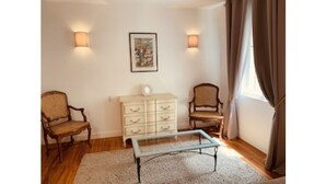A room with two wooden chairs, a white dresser, a glass-top coffee table, and a framed picture on the wall.