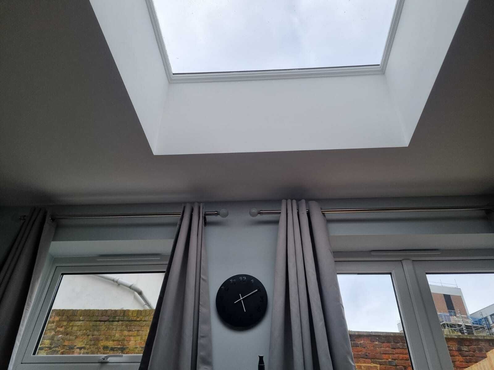 A room with a skylight, two windows, and a wall clock.