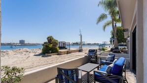 Une terrasse avec mobilier d’extérieur, un barbecue et une vue sur la plage et l’océan.
