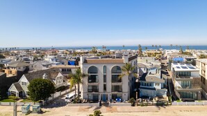 Un quartier résidentiel situé sur la côte, avec un imposant bâtiment blanc caractérisé par des fenêtres en arc de cercle et un toit plat.