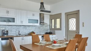 Eine moderne Küche mit weißen Schränken, einer Ziegelfassade und einem Essbereich mit einem Holztisch und Stühlen.