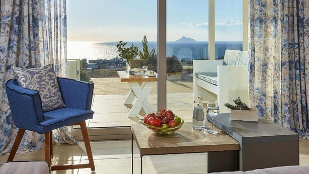 Ein moderner Sitzbereich im Freien mit Blick auf das Meer und ein Berg.