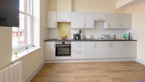 Una cocina moderna con armarios blancos, horno integrado y una ventana con plantas en macetas.