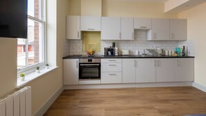 Una cocina moderna con armarios blancos, horno empotrado y una ventana con plantas.