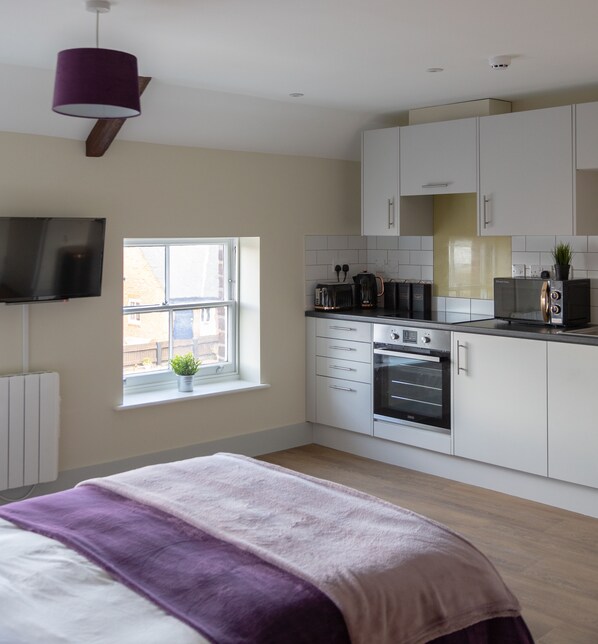 A modern kitchen with white cabinets, a built-in oven, and a window with a view of the outside. - HEREFORD CITY CENTRE – Apartment 10: Modern 1-Bed in City Centre, Sleeps 2 (Hereford)