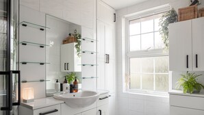 A modern bathroom with white cabinetry, a glass sink, and a large window providing natural light. - HEREFORD CITY – St Owens Terrace: Spacious 3-Storey Home, Walk to Centre (Hereford)