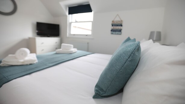 A bedroom with a bed, a TV, a dresser, and a window. - EXMOUTH, DEVON - Apt 2, Strand House: 2 Bed, Central Location, Sleeps 6, (Exmouth)