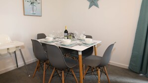 A dining area with a table set for four, including wine glasses and a bottle of wine. - EXMOUTH, DEVON - Apt 2, Strand House: 2 Bed, Central Location, Sleeps 6, (Exmouth)