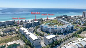 Een kustresortgebied met meerdere gebouwen, waaronder een groot hotel met zwembad en een kleiner gebouw met de aanduiding 'Condo'. Duidelijke paden leiden naar het strand, wat de toegang tot het strand aangeeft.