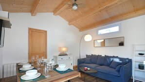 Un coin repas avec une table en bois dressée pour quatre personnes, un canapé bleu et un ventilateur de plafond.