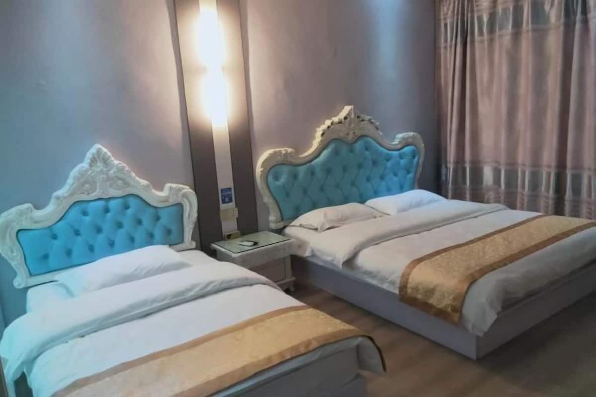A hotel room with two beds, each with a tufted headboard, a bedside table, and a lamp.