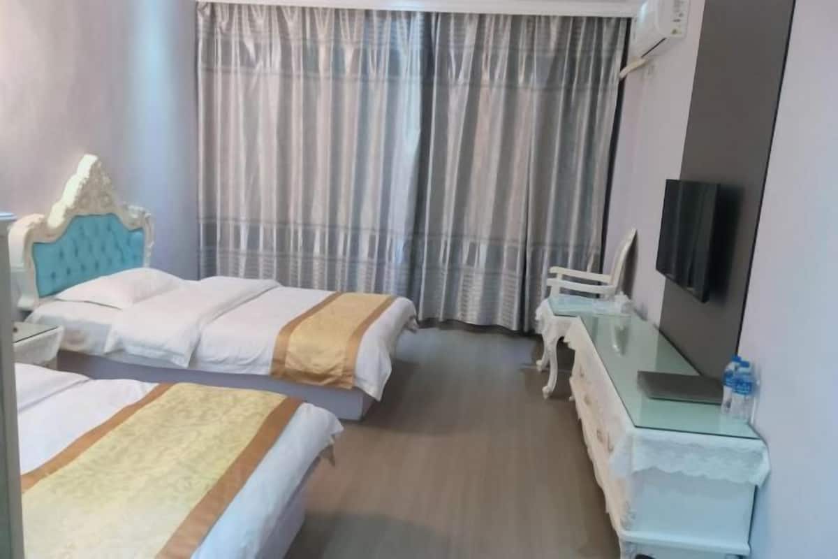 A hotel room with two beds, a TV, a dresser, and a window with curtains.