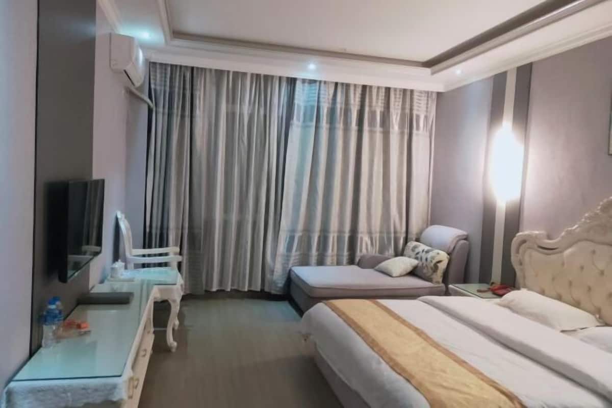A hotel room with a bed, a chair, a desk, a television, and a large window with curtains.