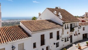 Un bâtiment blanc, doté d’un toit en tuiles et de nombreuses fenêtres, qui offre une vue sur la côte.
