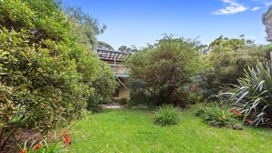 A lush garden with a variety of plants and a wooden deck. - Frankie - A wonderful place to escape the city (Skenes Creek)