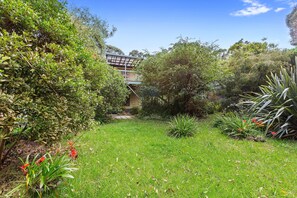 A lush garden with a variety of plants and a wooden deck. - Frankie - A wonderful place to escape the city (Skenes Creek)