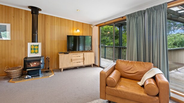 A cozy living room with a fireplace, a leather sofa, and a large window with curtains. - Frankie - A wonderful place to escape the city (Skenes Creek)