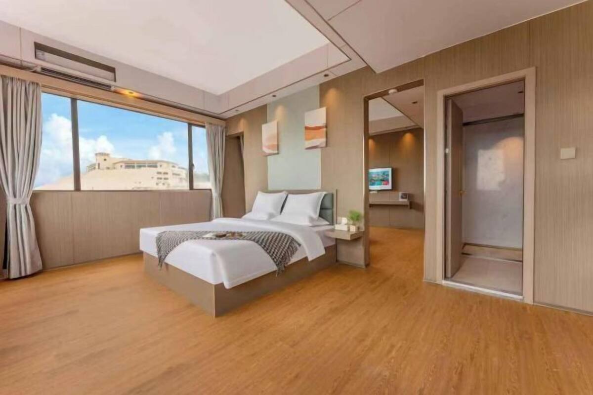 A modern hotel room with a large bed, a TV, and a view of the city.