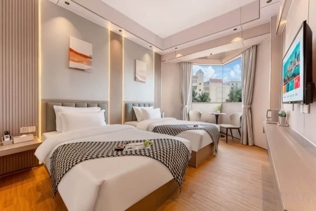 A hotel room with two beds, a balcony, a TV, and a window with a view.